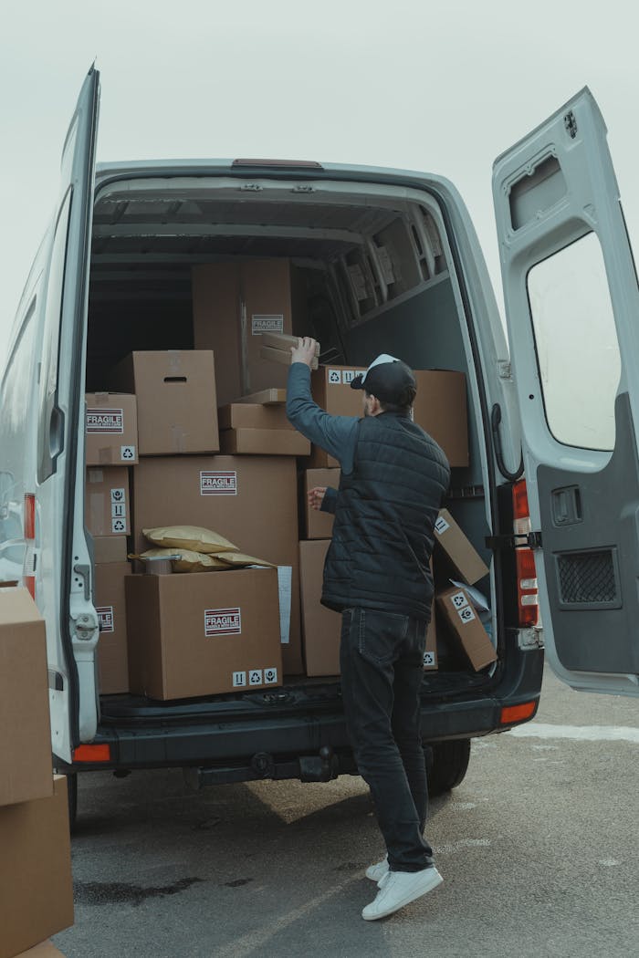 digital A courier organizing boxes in a delivery van for shipment on a cloudy day.